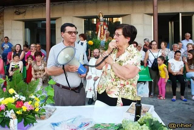 Una vecina ayuda al p&aacute;rraco durante la subasta para San D&aacute;maso en Valverde del Fresno. Una imagen de ANHER publicada en www.sierradegatadigital.es                            