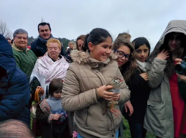 Una niña sonríe con la perdiz entre sus manos antes de soltarla en Villanueva de la Sierra
