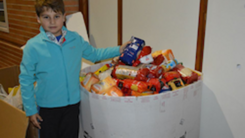 Un niño muestra los alimentos recogidos en Torneo Solidario ADV